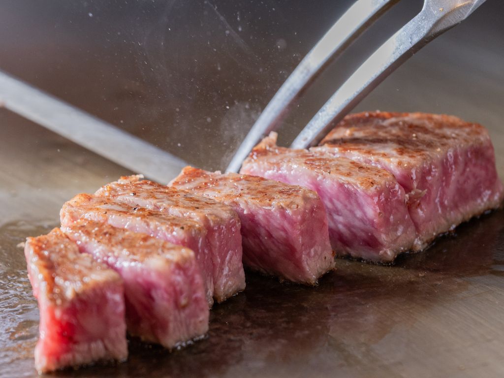 鉄板で焼かれる霜降り和牛ステーキ、湯気が立ち上る